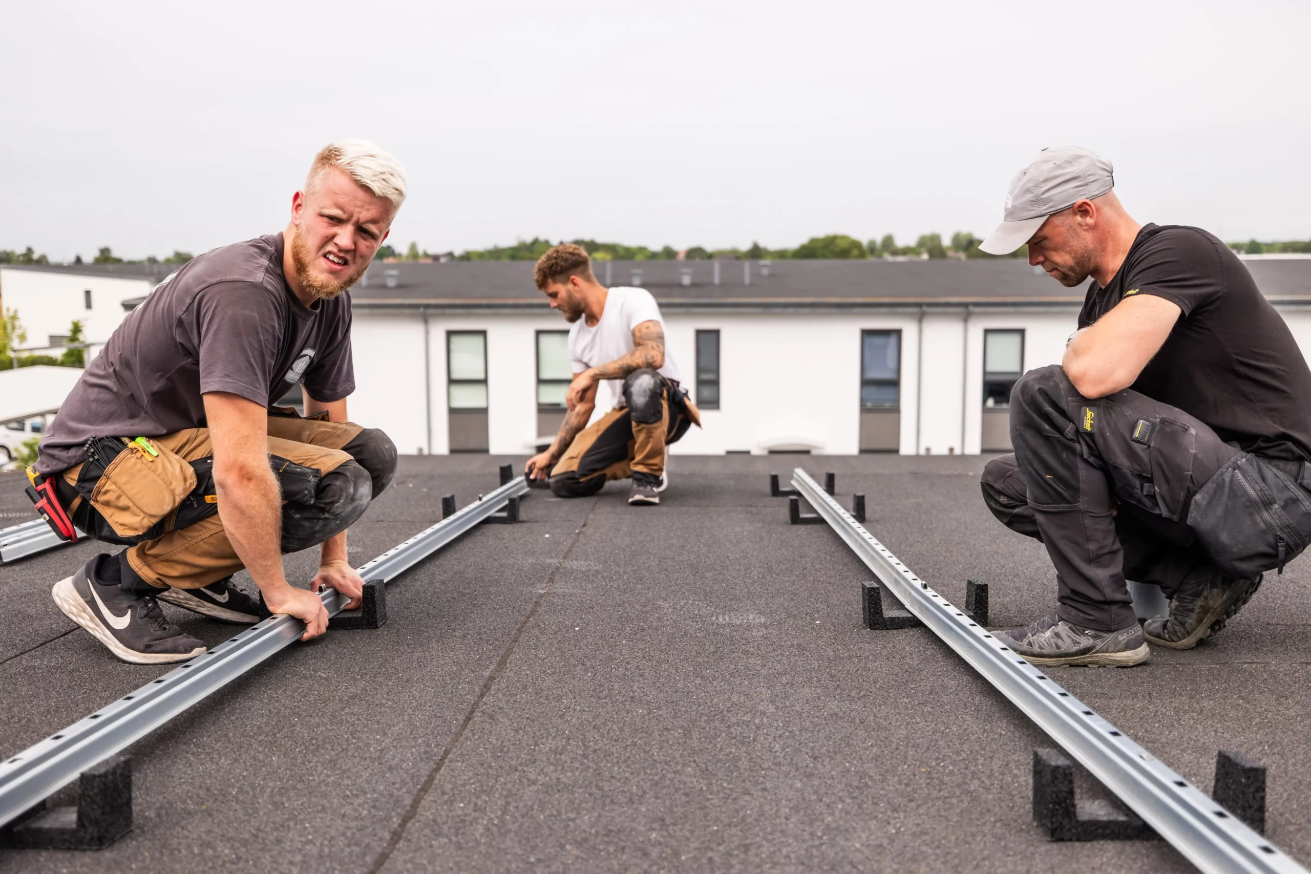 Tre montører sidder på taget og monterer solcelleanlæg